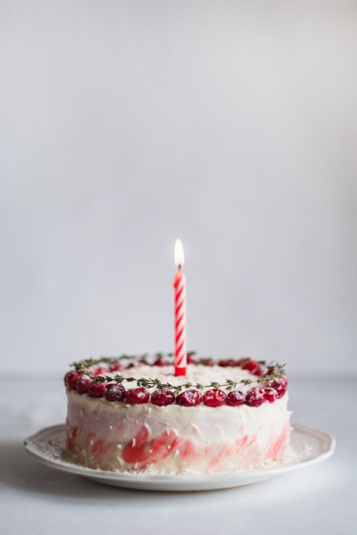 white and pink covered cake with lightened candle