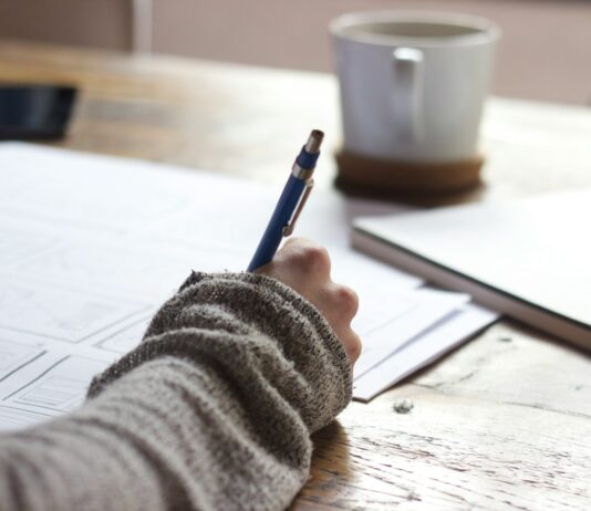 영어를 단계적으로 체계적 공부하는 방법 person writing on brown wooden table near white ceramic mug