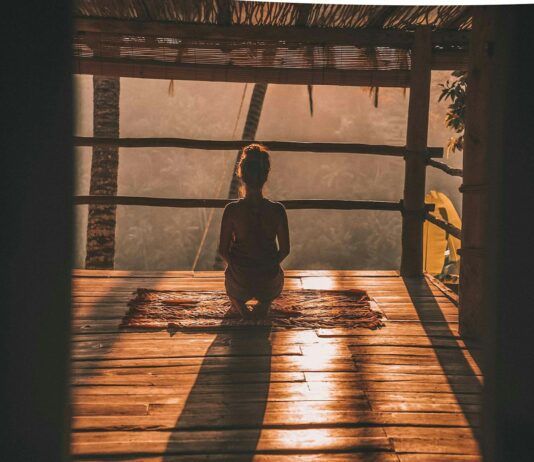 명상과 호흡법이 스트레스 해소에 미치는 영향 woman meditating on floor with overlooking view of trees