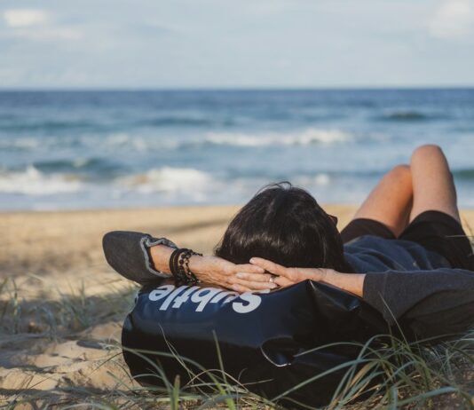“주말만 되면 더 피곤해지는 이유”…과도한 ‘휴식’이 피로를 만든다 woman lying on grass front of sea at daytime
