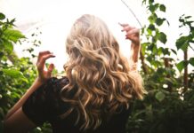 blonde haired woman in black top surrounded by tall plants