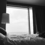 grayscale photo of bed near white table lamp
