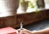 “스트레스, 자연스럽게 풀기… 새롭게 떠오르는 ‘슬로우 라이프’ 실천 팁” a person writing on a piece of paper with a pen